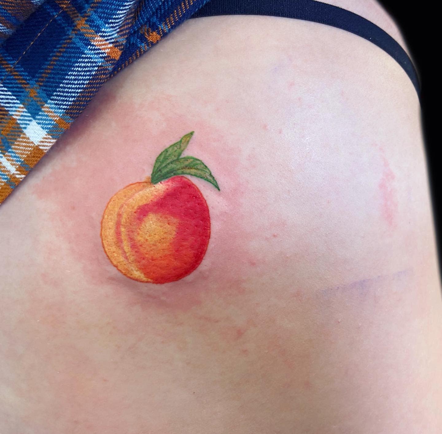 A small, colorful peach tattoo on skin